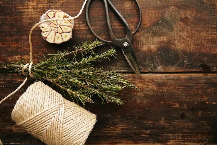Vintage scissors, twine, and rosemary on a rustic wooden worktable